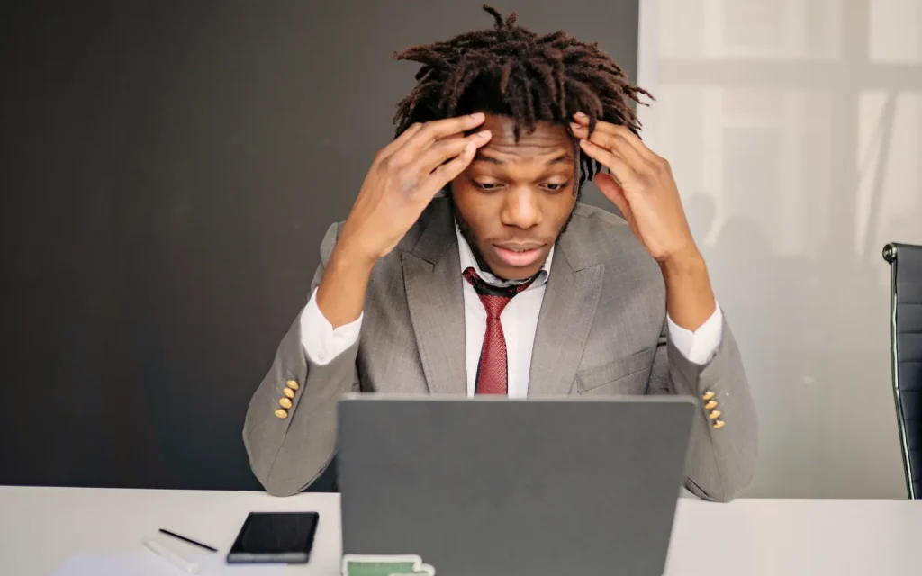 A man in a suit with head in hands struggling to concentrate, representing mold toxicity symptoms in an office environment